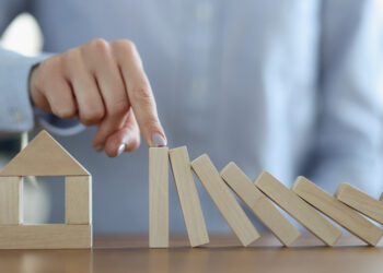 Business woman stoping falling wooden blocks in front of house closeup. Real estate insurance concept