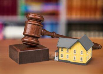 Close-up of wooden gavel with little model of house. Justice concept