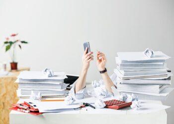 The conceptual image or collage about many of crumpled papers on the desk of stressed male workplace
