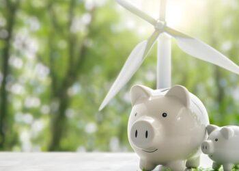 Ecofriendly wind turbine symbolizes sustainable living and energy savings beside piggy bank. Concept Ecofriendly living, Sustainable energy, Savings, Wind turbine, Piggy bank