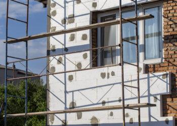 Scaffold on house, renovation. House for renovation with the scaffolding for workers on building, close up