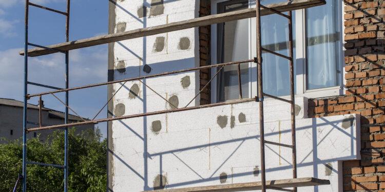 Scaffold on house, renovation. House for renovation with the scaffolding for workers on building, close up