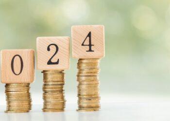 stack of coins on wooden table with new year message 2024 business growth new beginning