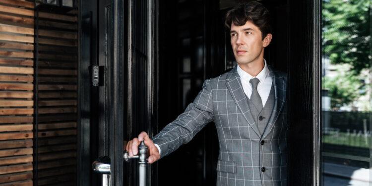 Successful middle aged businessman in suit leaving office building