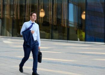 Tired young businessman with case going after work in hot weather
