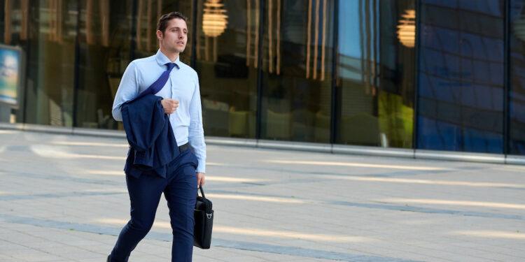 Tired young businessman with case going after work in hot weather